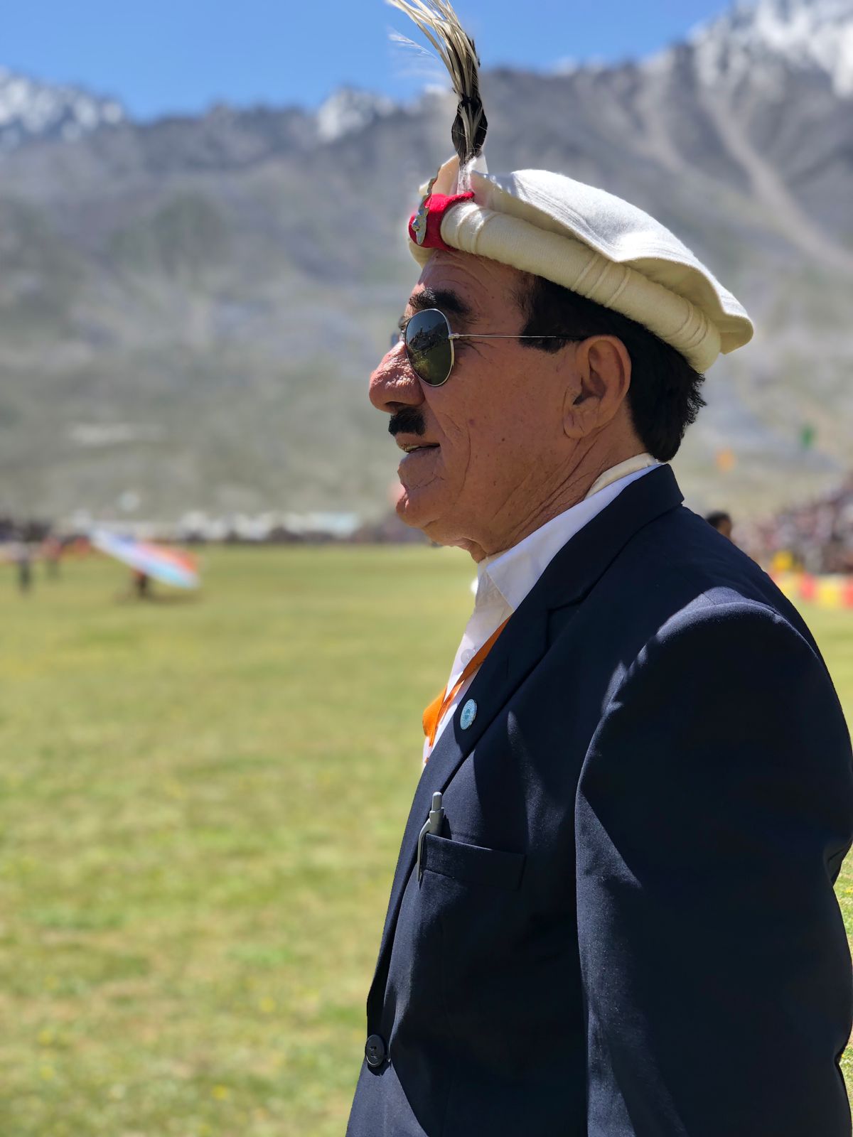 Amir Ullah Khan Yaftali at Shandur in Chitrali cap with mountains behind