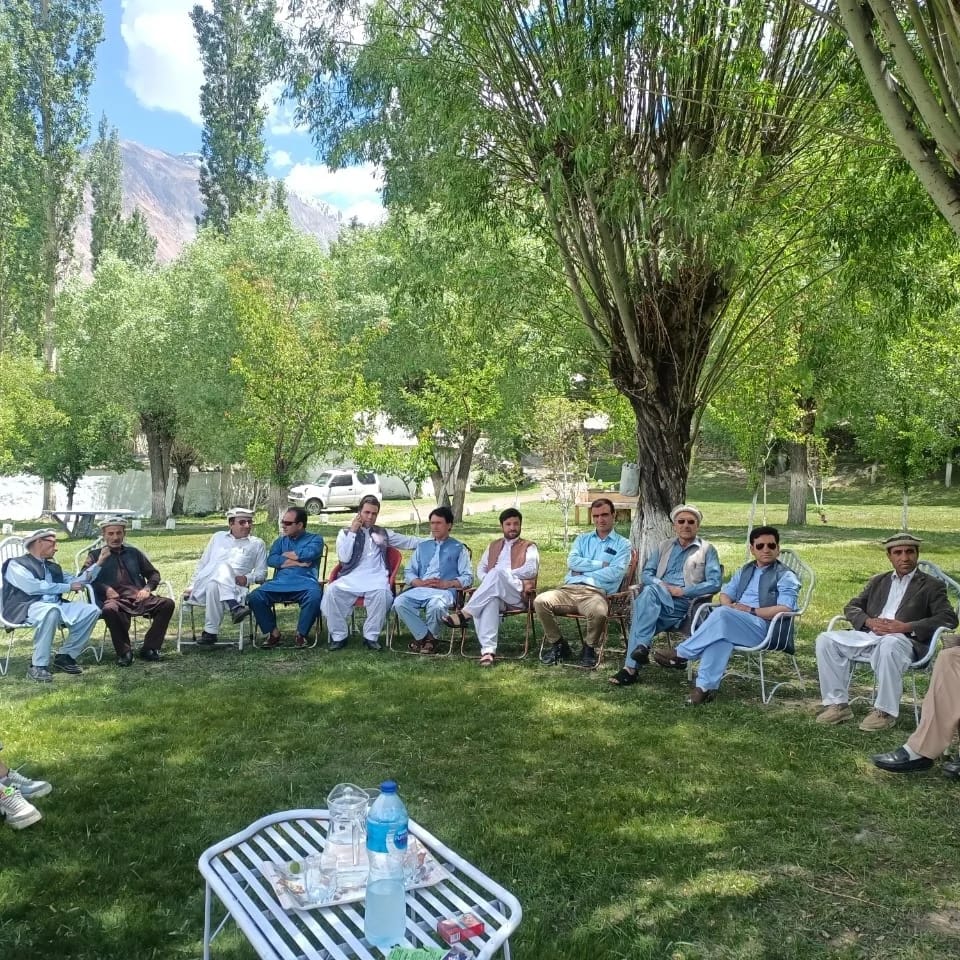 Community members seated under trees in valley