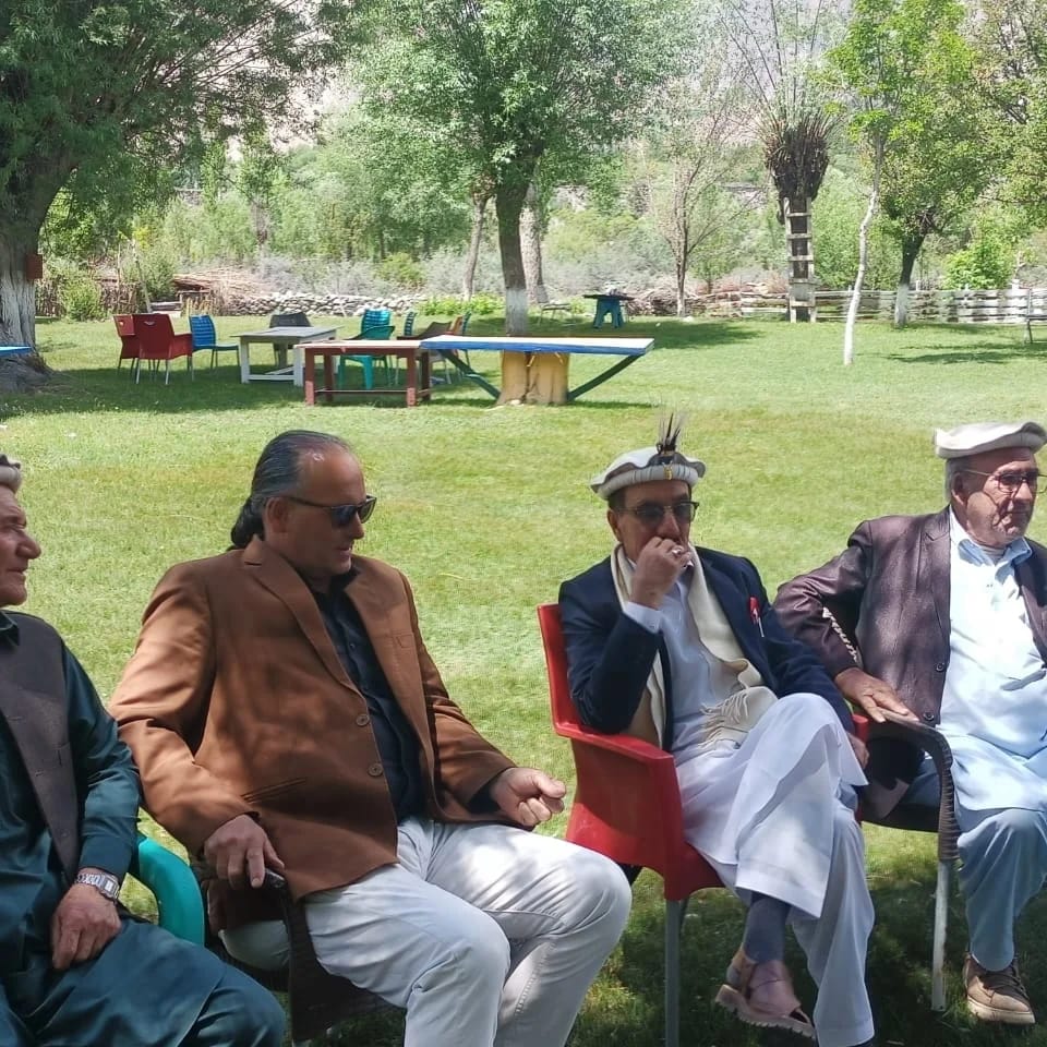 Community elders conversing in a garden setting in Chitral