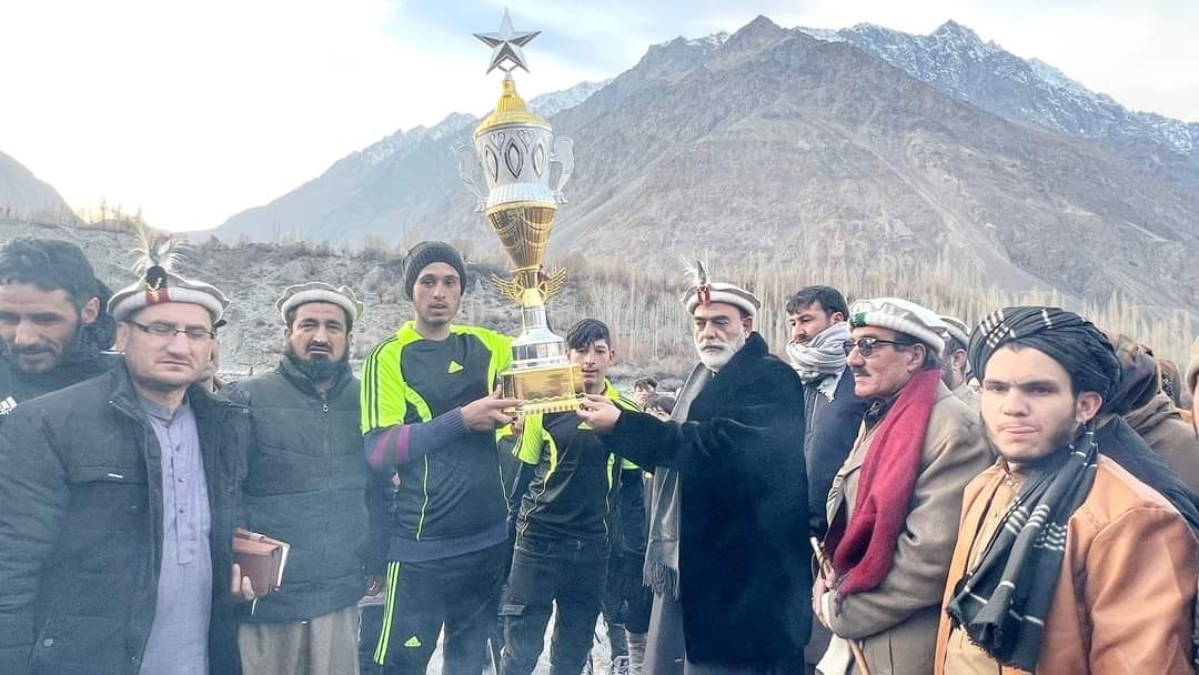 Community members holding trophy at mountain pass ceremony