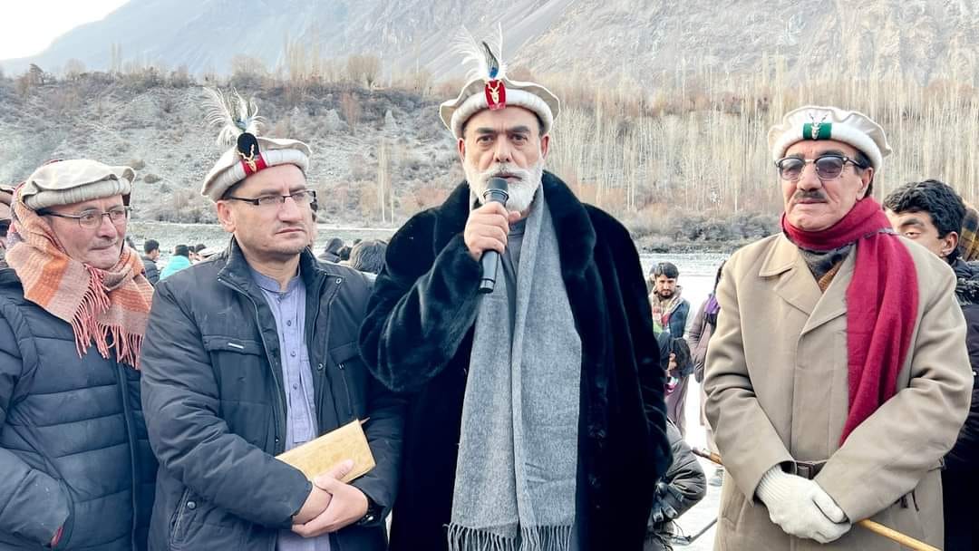 Community leader addressing a gathering in a mountain valley in winter
