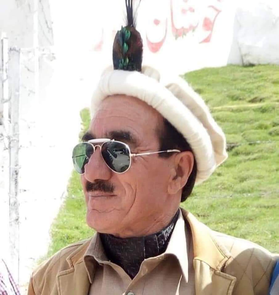 Elder community member wearing a traditional Chitrali cap with peacock feather