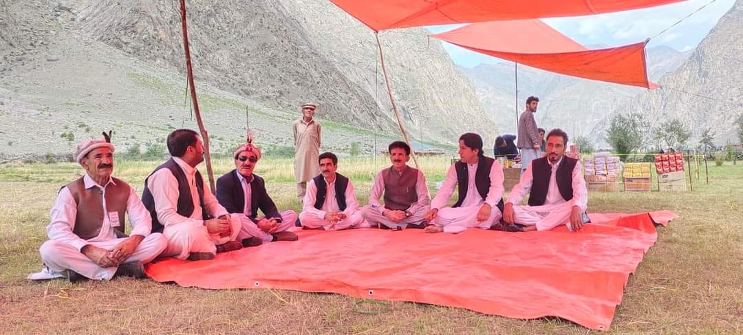 Community leaders meeting under a tent in a mountain valley in Chitral