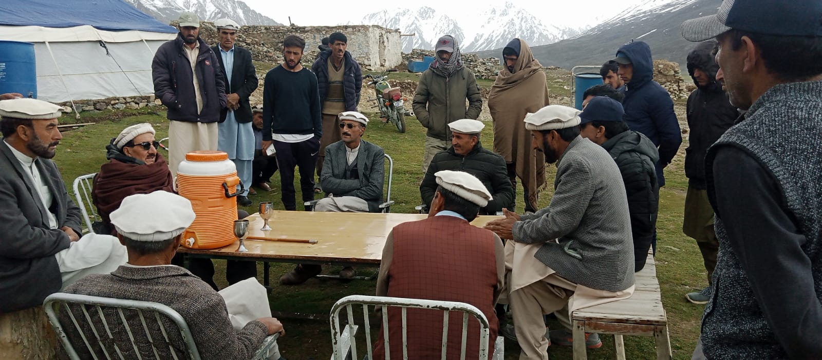Community meeting around a table in a high-altitude settlement near Shandur