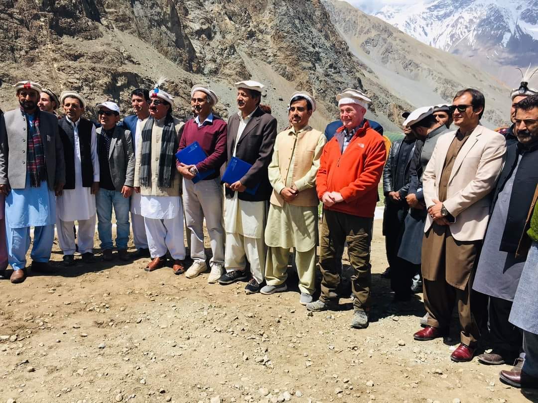 Community delegation posing for a group photo at a mountain site in Chitral