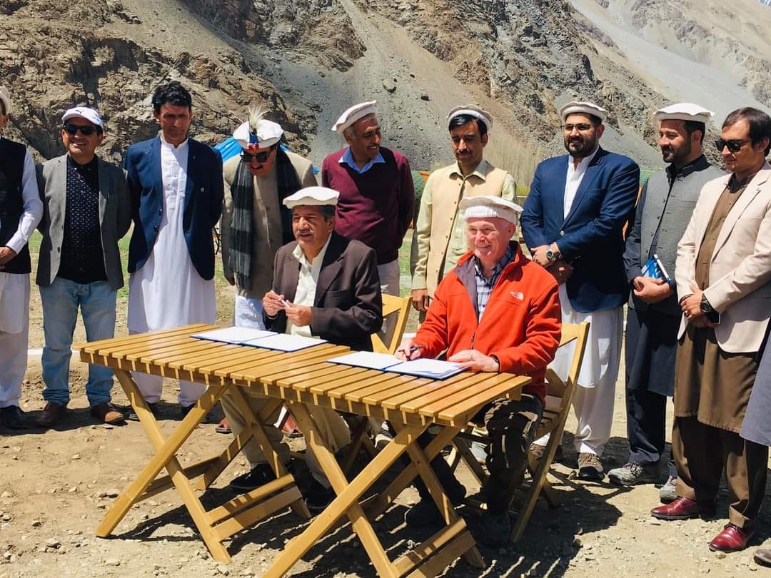 Officials in formal line at mountain base with snow peaks