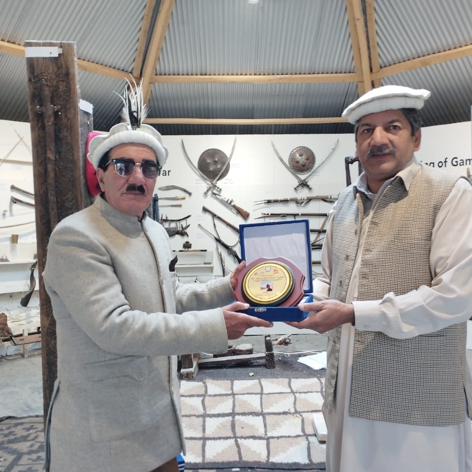Two men presenting golden award plaque in museum setting