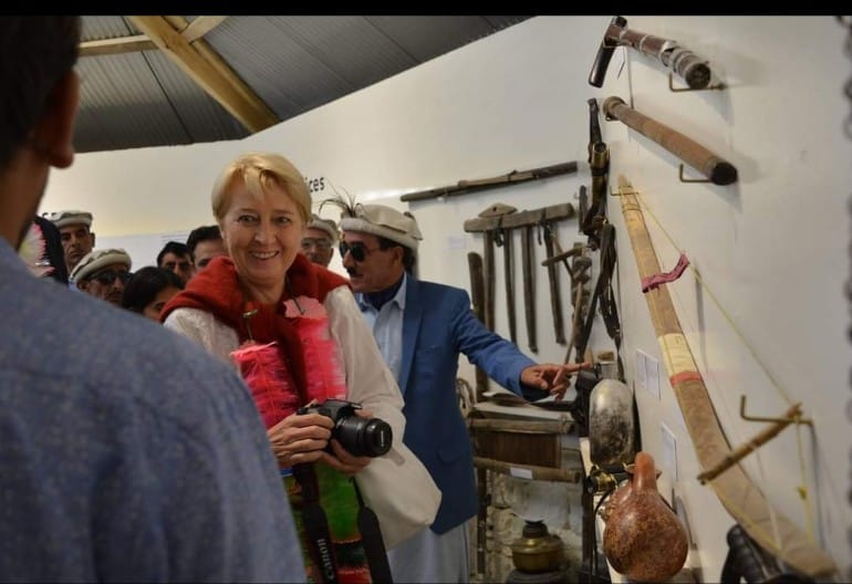 Woman examining traditional polo tools and weapons on museum wall