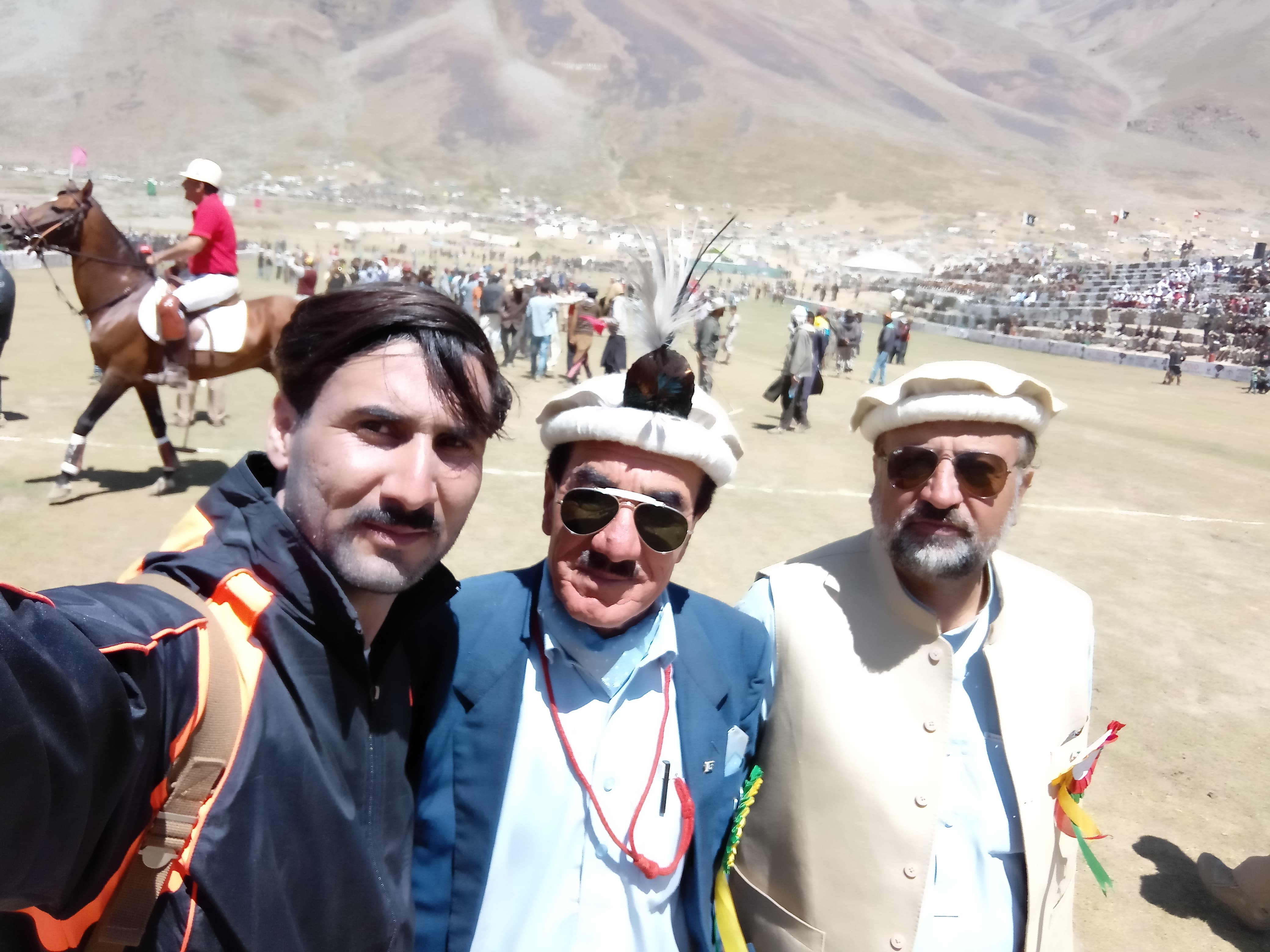 Four men conversing at Shandur Polo grounds with mountains