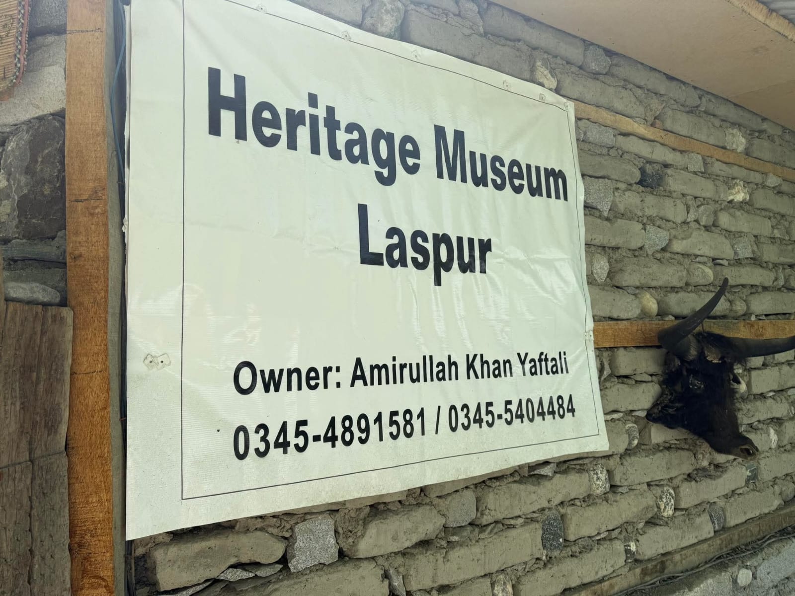 Two men at museum building entrance with Pakistani flag